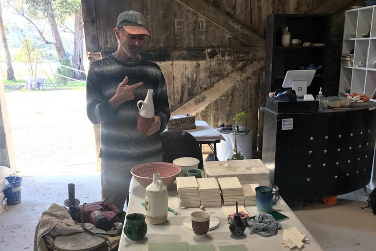 un uomo in piedi in una stanza con un tavolo con ceramiche