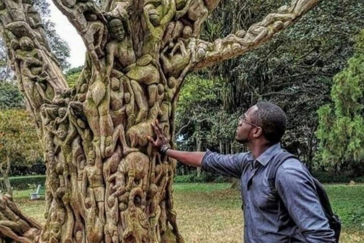 un bărbat care stă lângă o sculptură a unui copac
