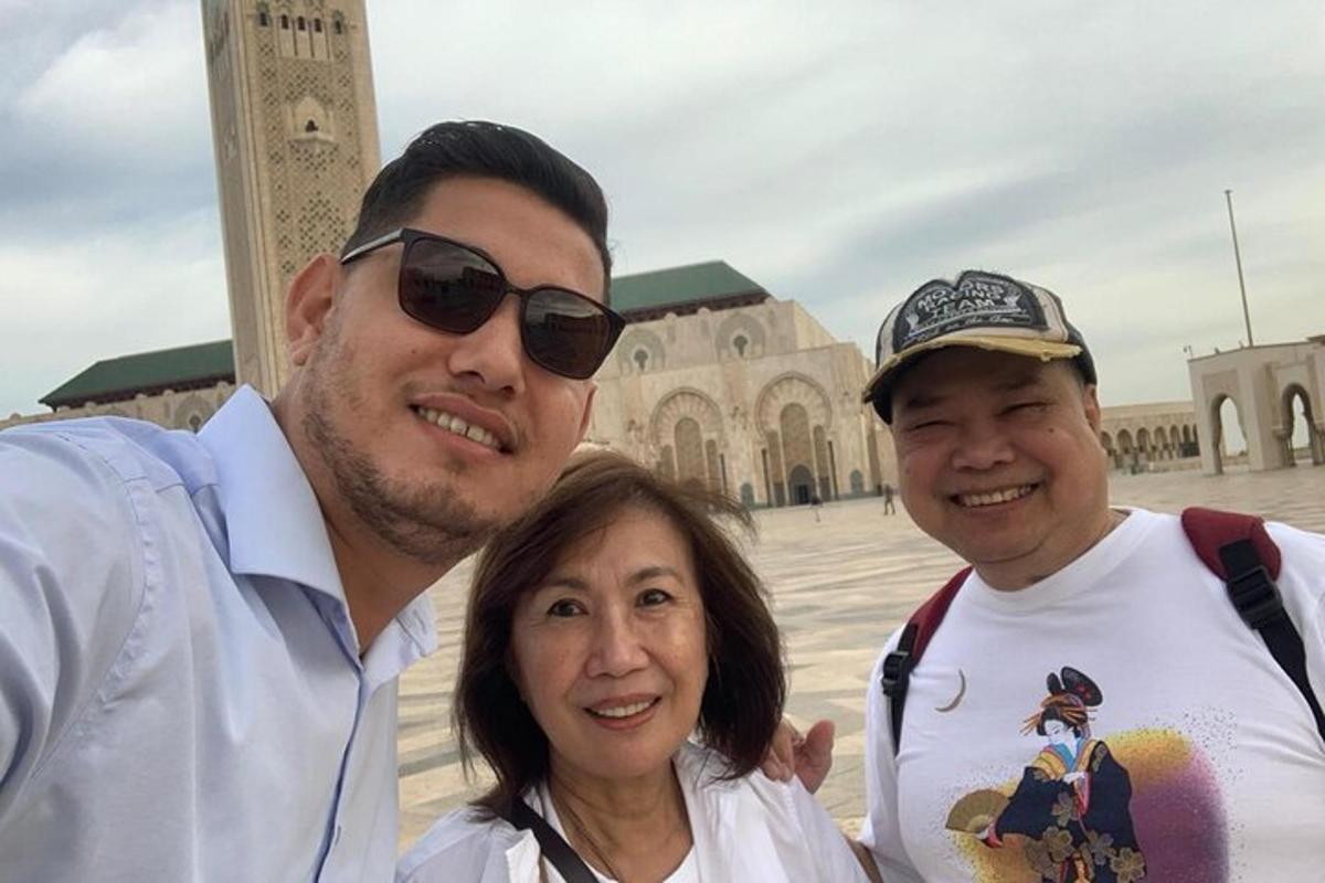 two men and a woman standing in front of a mosque