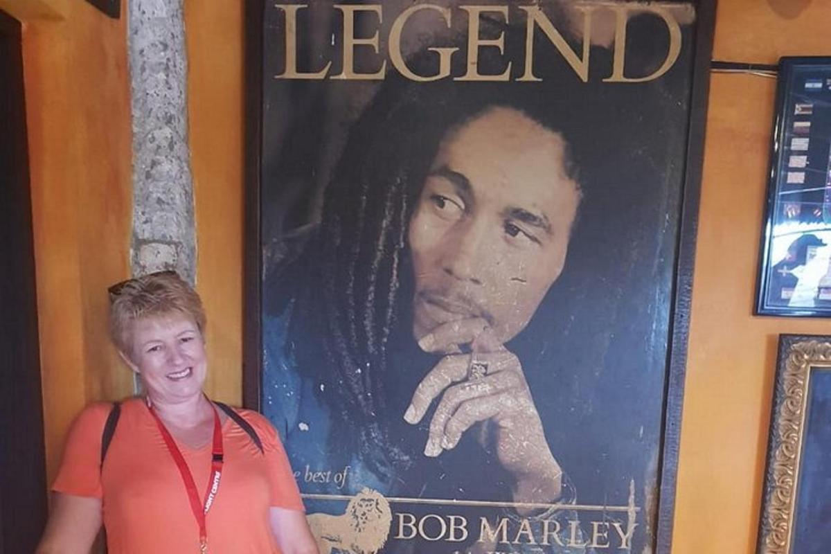 Kona stendur fyrir framan veggspjald af goðsagnakennda Bob Marley