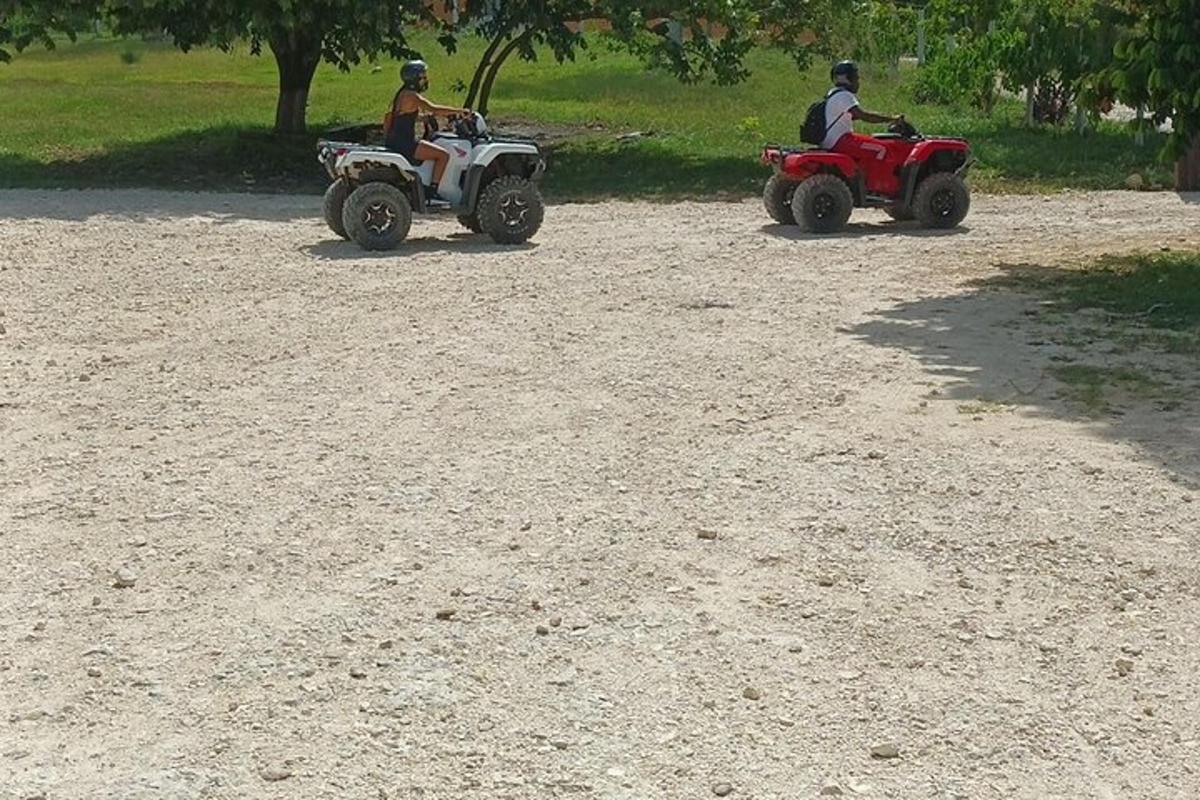 due persone in sella a quad su una strada sterrata