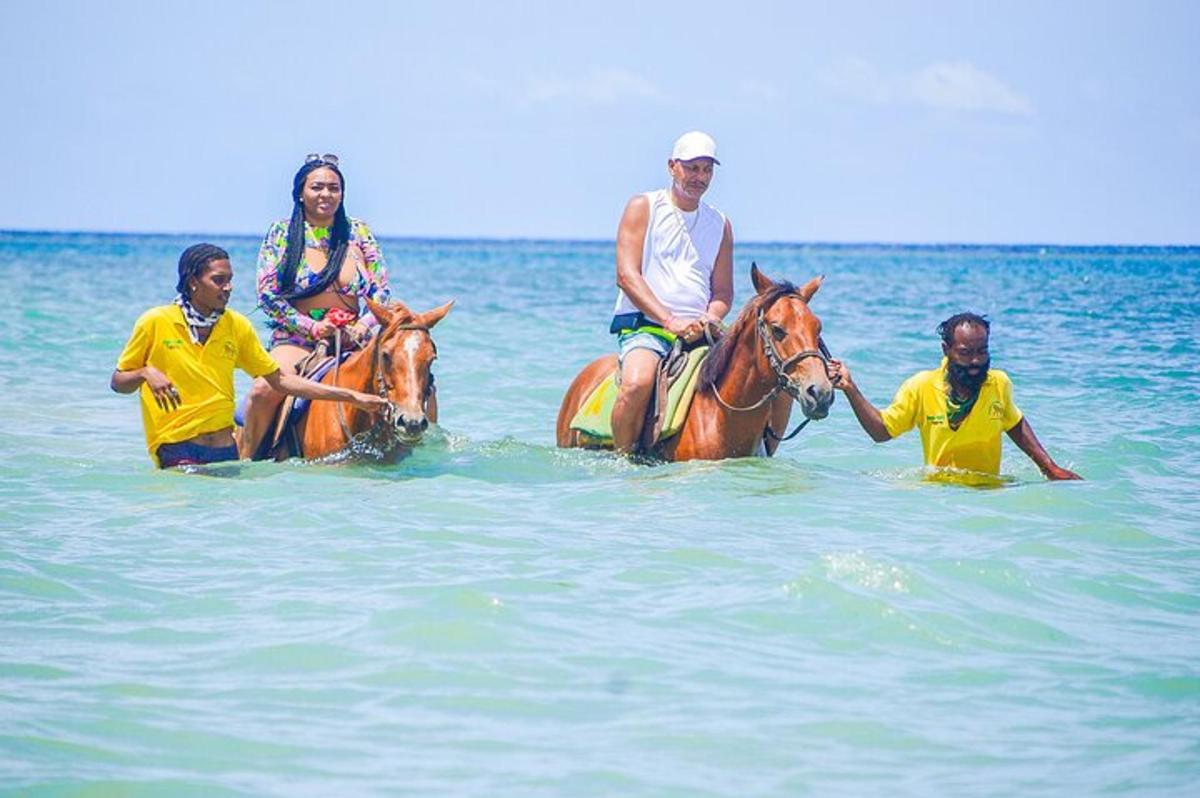 Un grupo de personas montando a caballo en el agua.