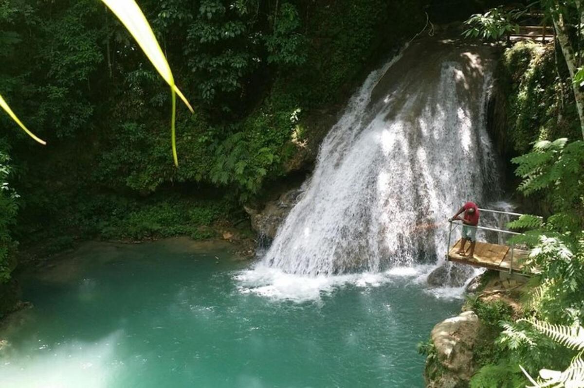 dua orang berdiri di jembatan di depan air terjun