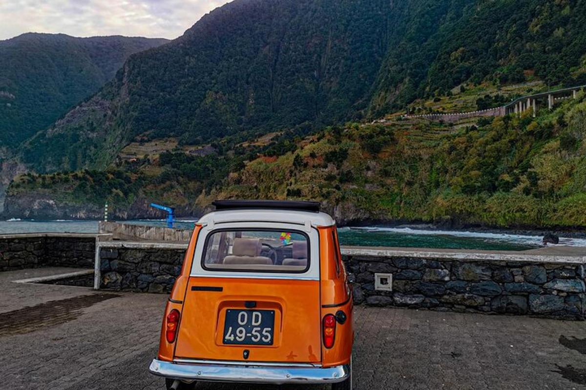 un'auto arancione e bianca parcheggiata accanto a una montagna
