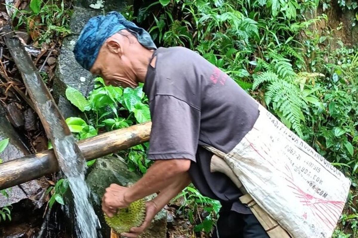 un uomo con un asciugamano in testa che beve acqua da un tubo