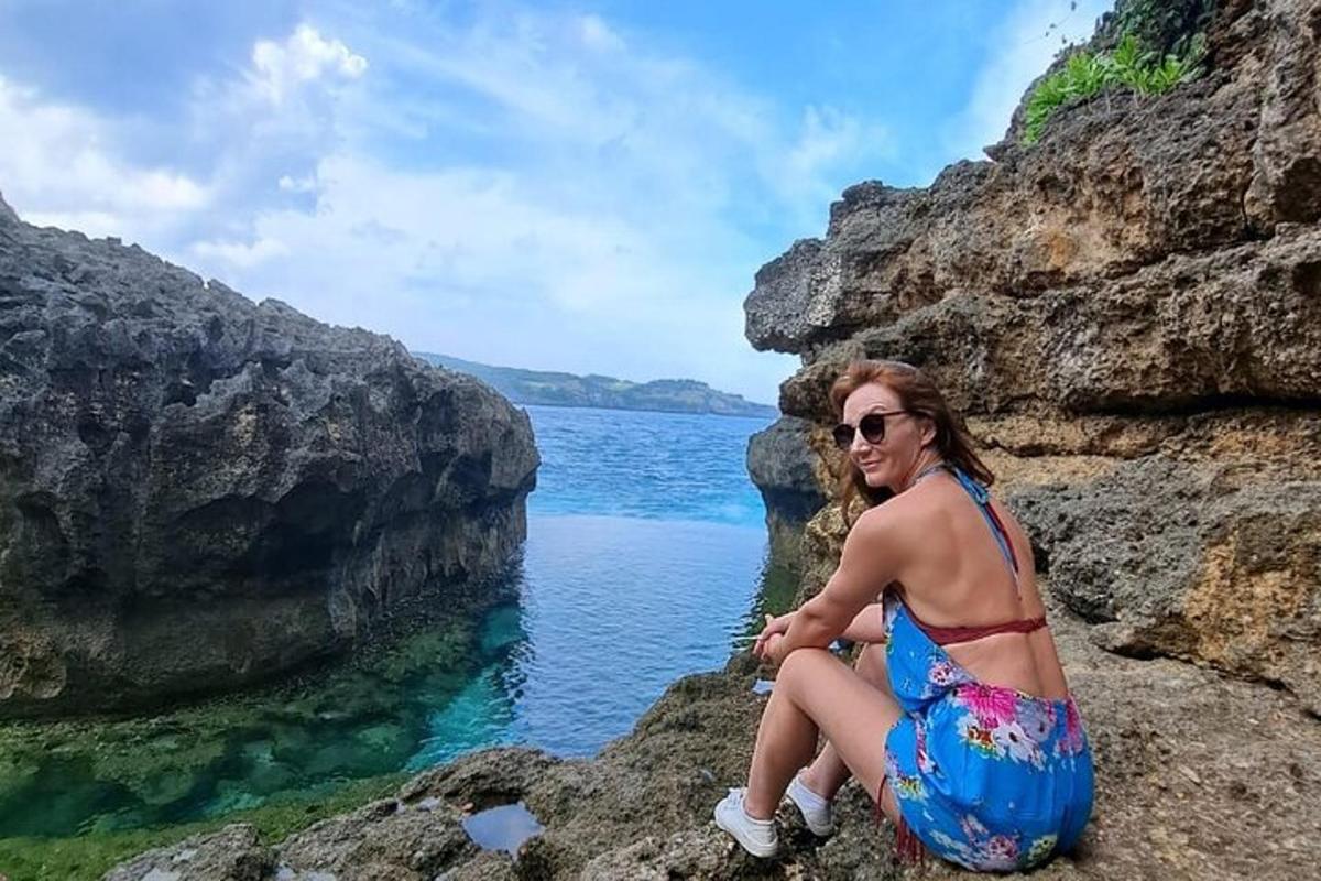 egy nő ül egy sziklán a víz közelében