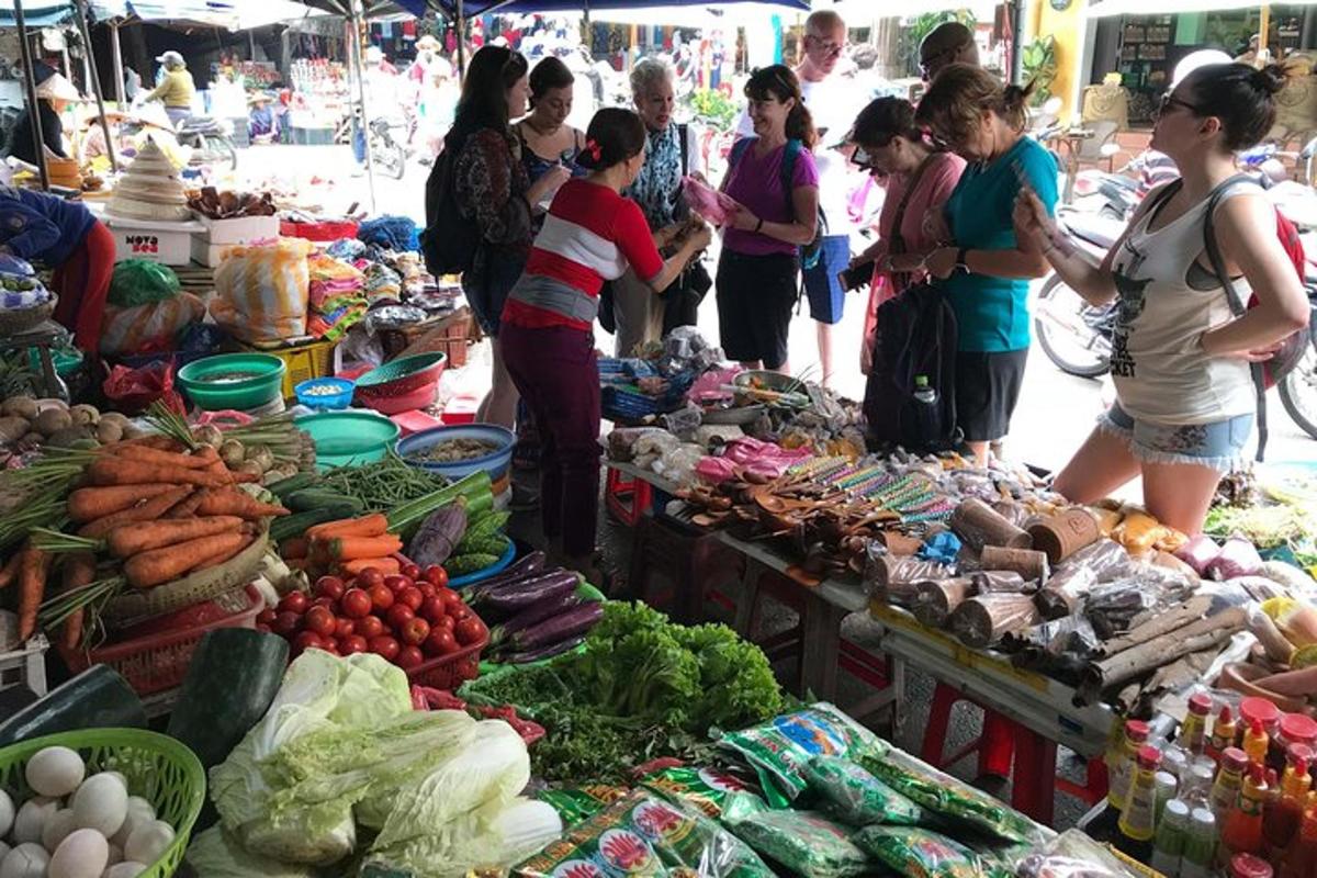 un gruppo di persone in piedi intorno a un mercato con le verdure