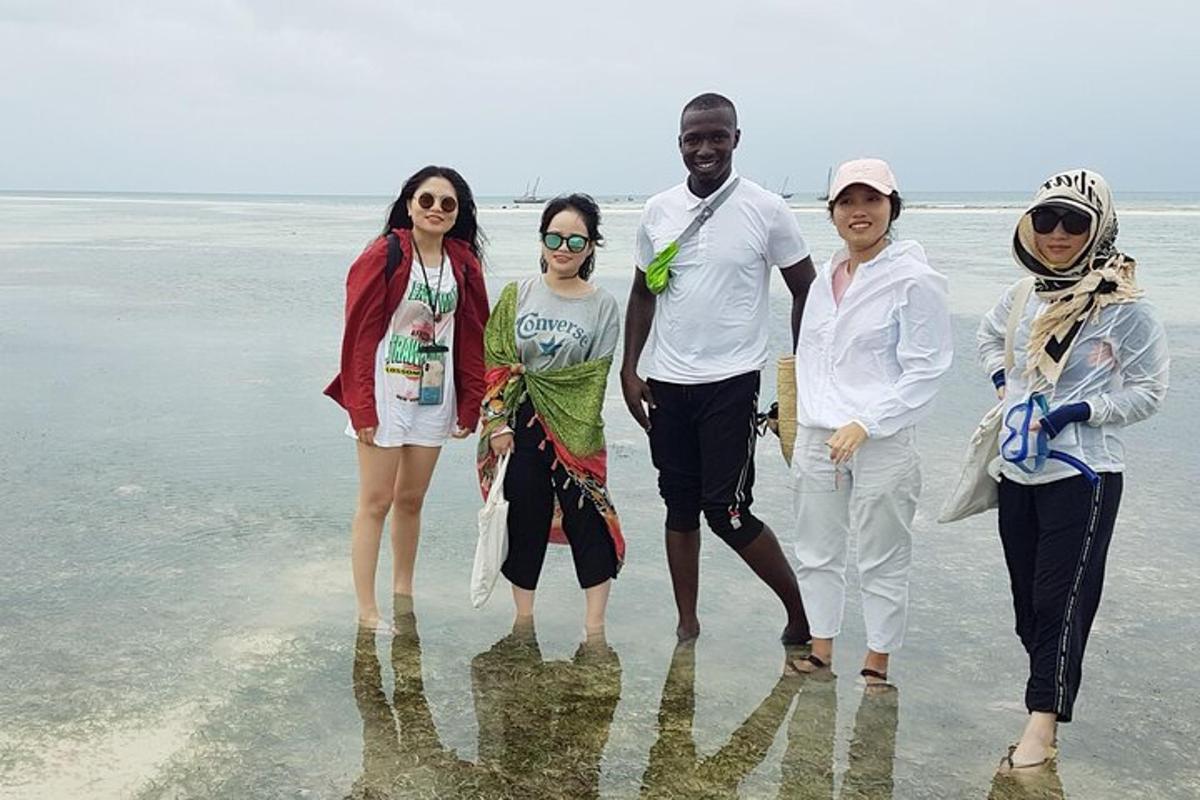 sekumpulan orang berdiri di dalam air di pantai
