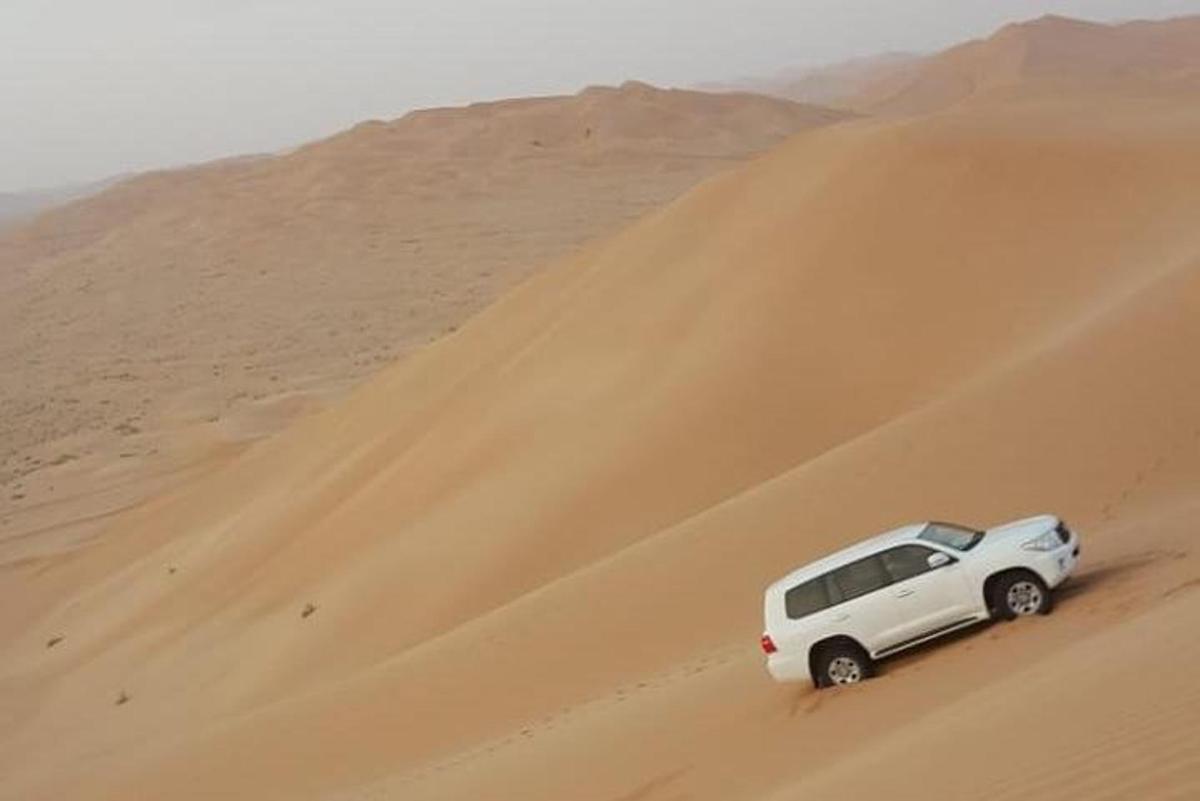 a white car driving down a sand dune in the desert