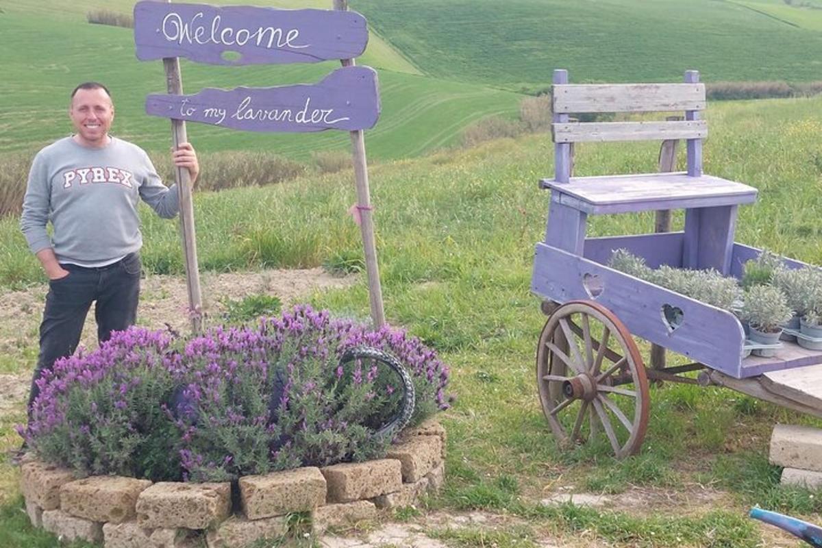 Un hombre de pie junto a un cartel junto a un jardín de flores.