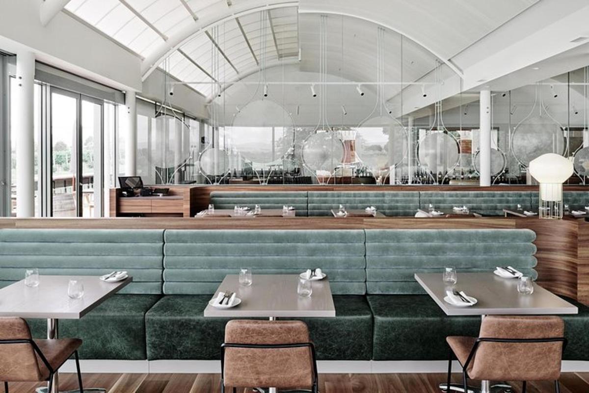 uma sala de jantar com um banco verde e mesas