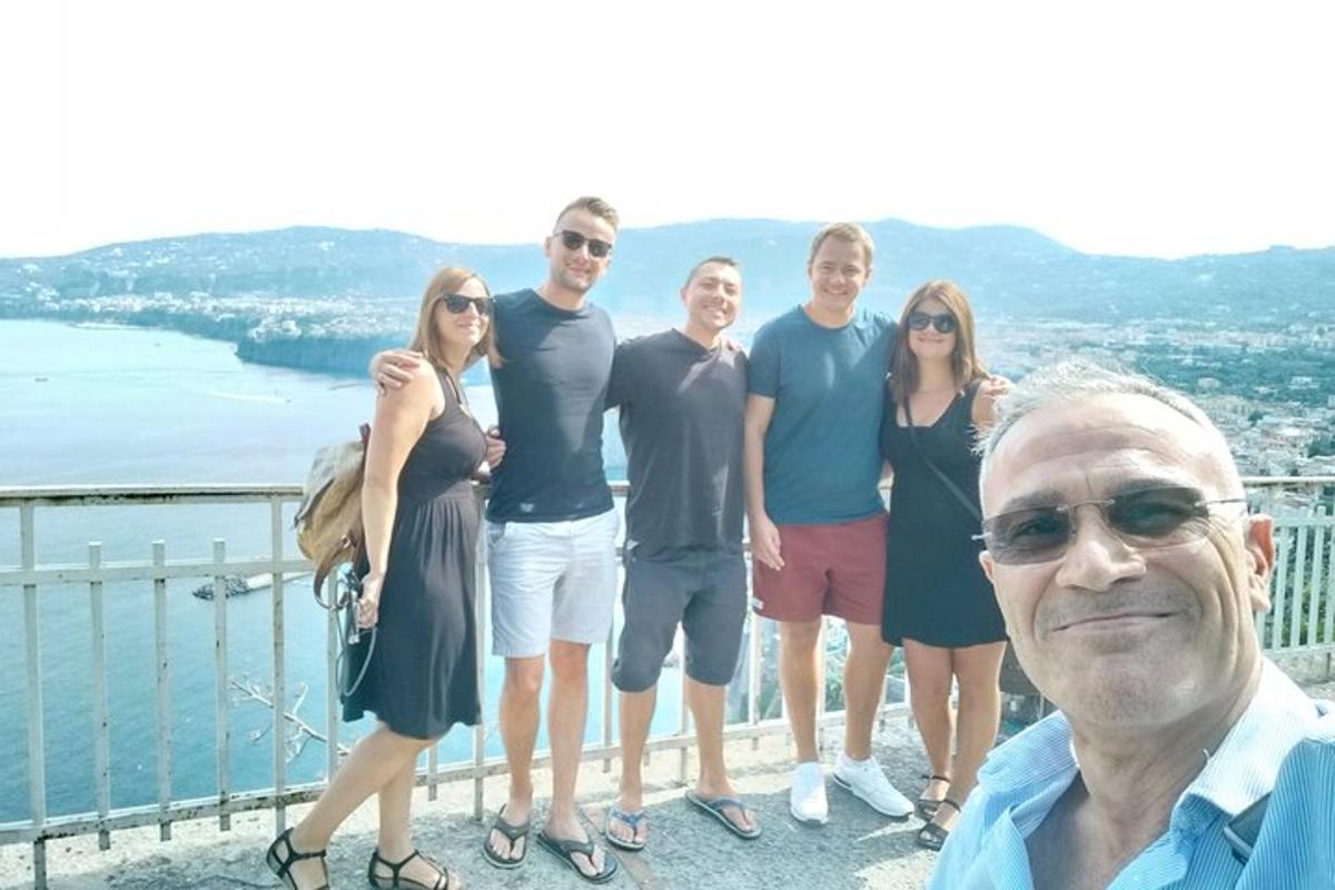 skupina lidí pózujících pro fotografii na balkóně
