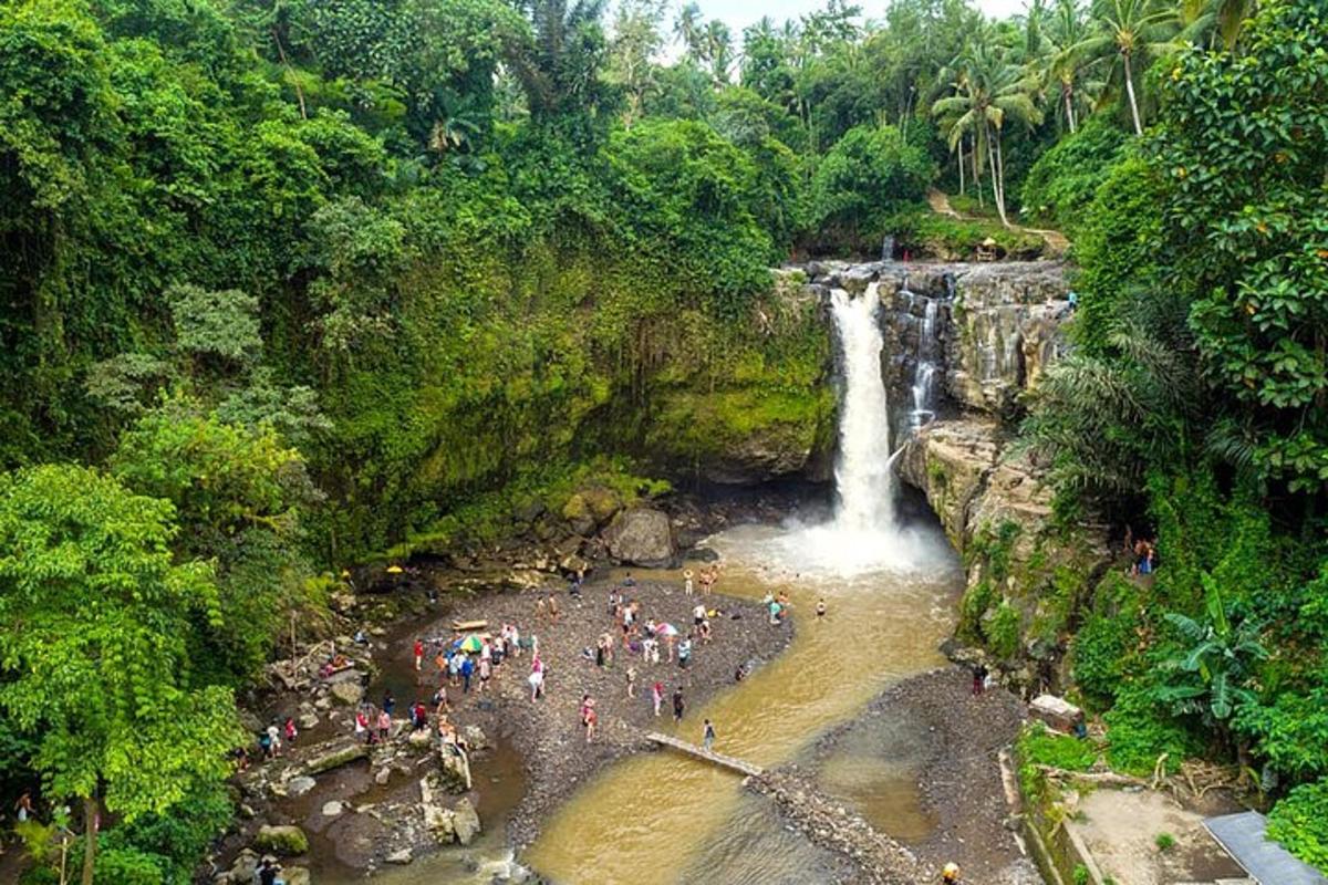 sekumpulan orang berdiri di dalam air berhampiran air terjun