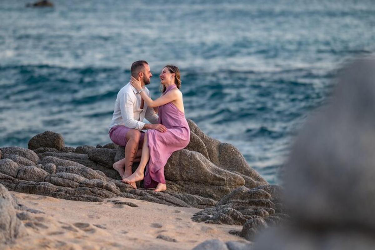 Un hombre y una mujer sentados en una roca en la playa