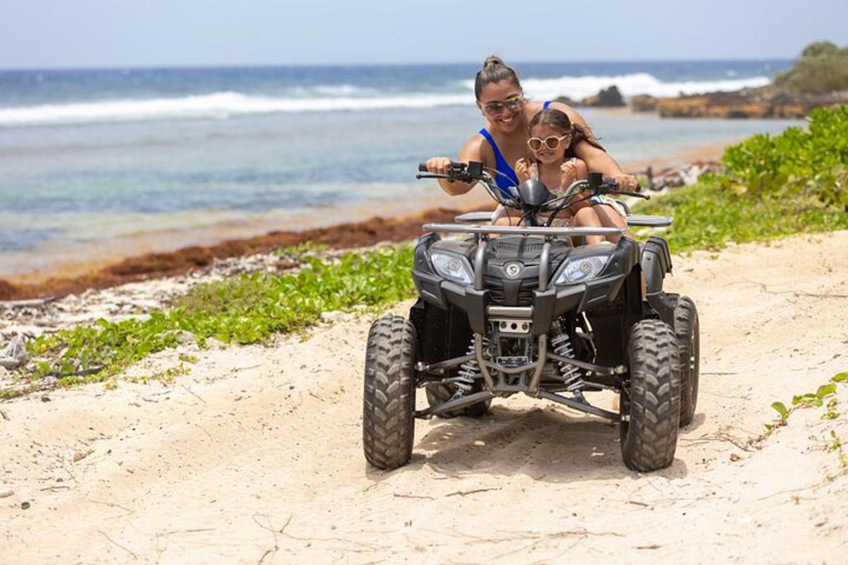 a man and a woman riding a quad bike on the beach