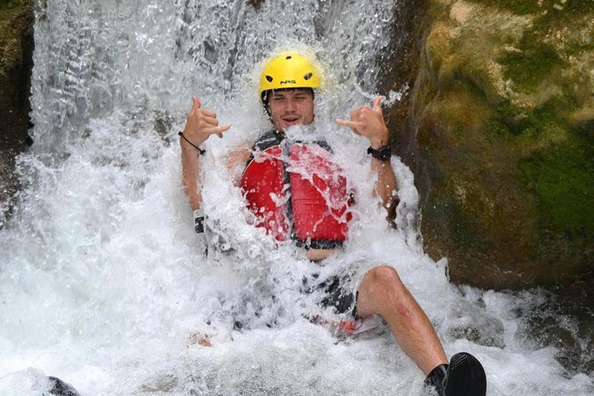 un home amb un casc groc assegut en una cascada