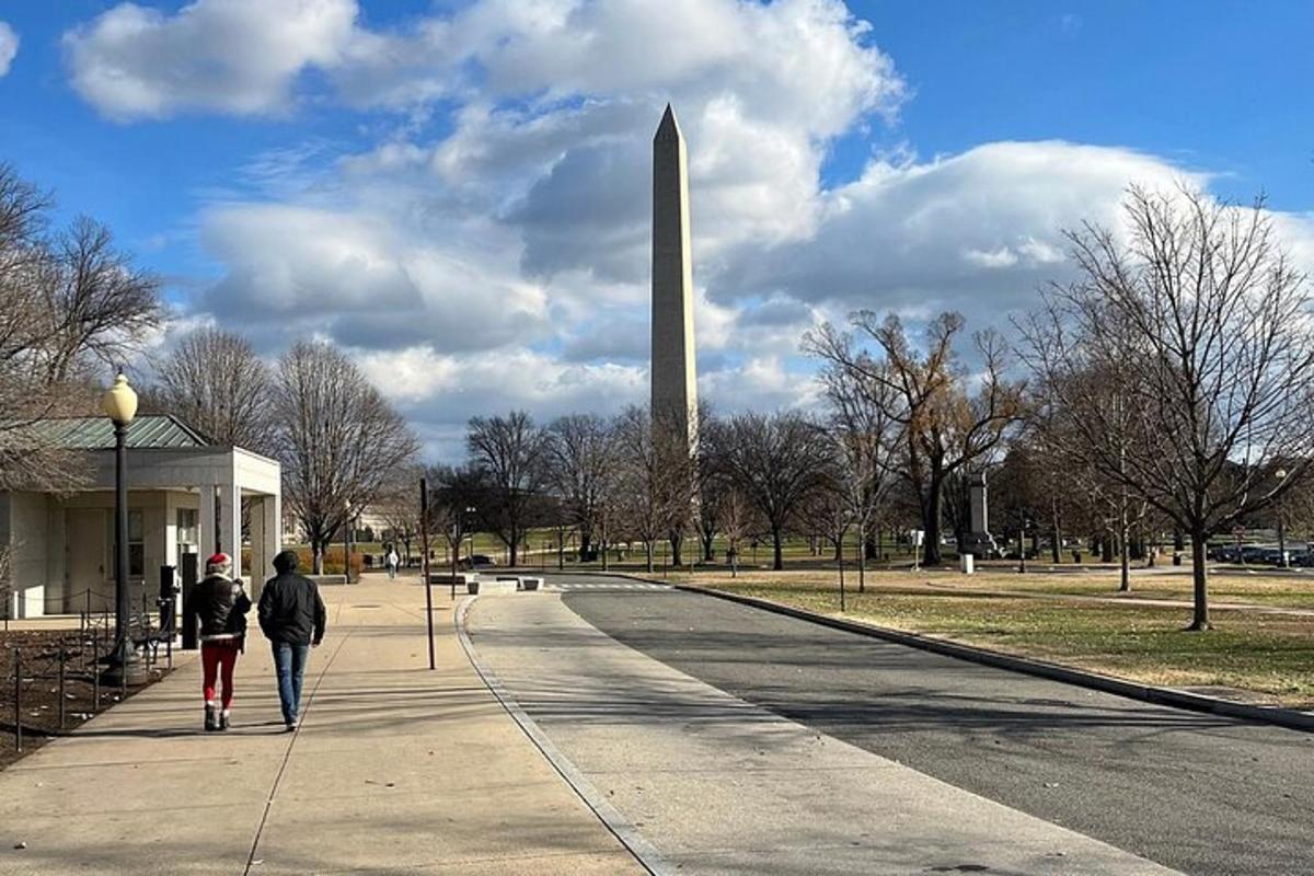 due persone camminano sul marciapiede davanti al monumento a Washington