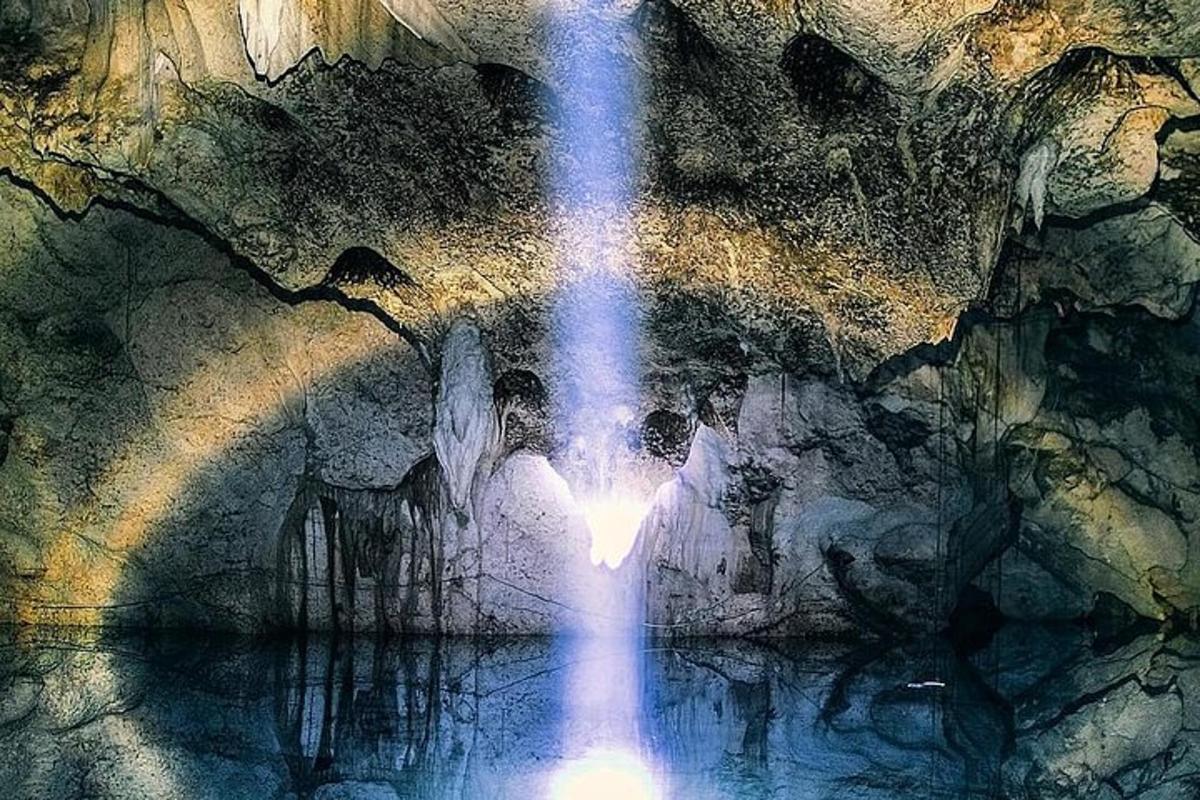 una cascata in una grotta con persone in piedi nell'acqua