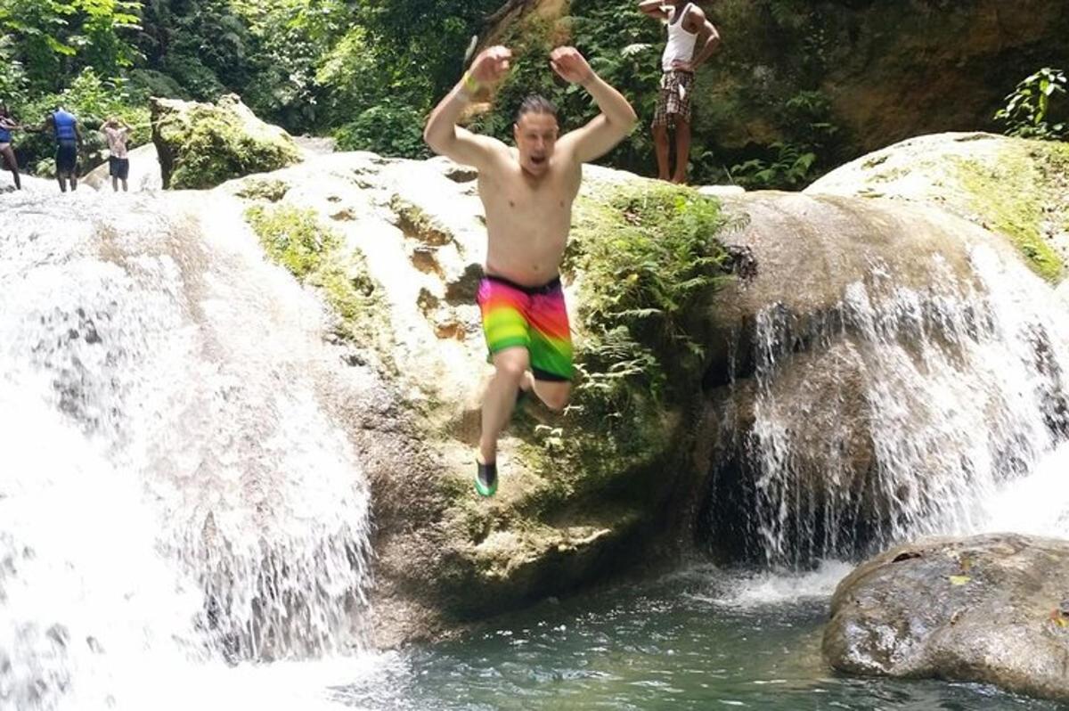 um homem pulando de uma cachoeira na água