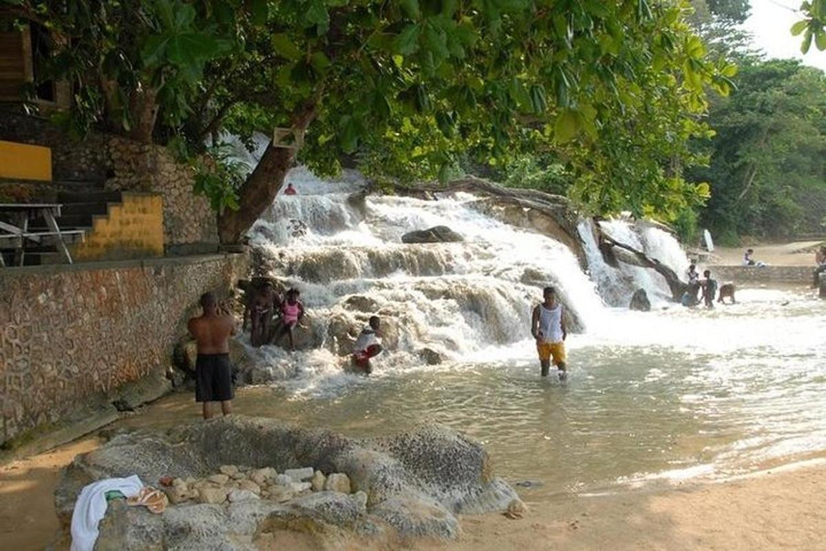 sekumpulan orang berdiri di dalam air berhampiran air terjun