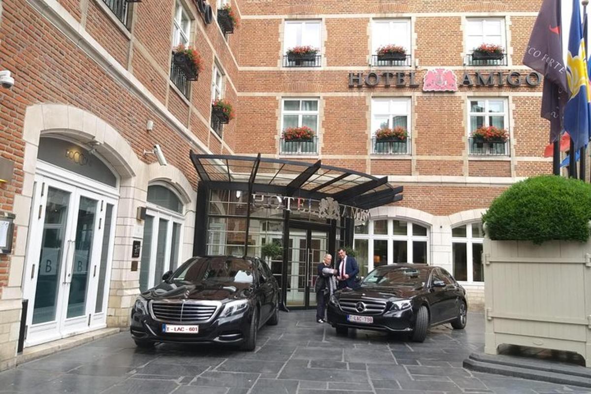două persoane stând în fața unui hotel cu două mașini