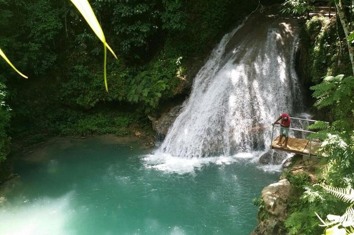 seseorang berdiri di jembatan di depan air terjun