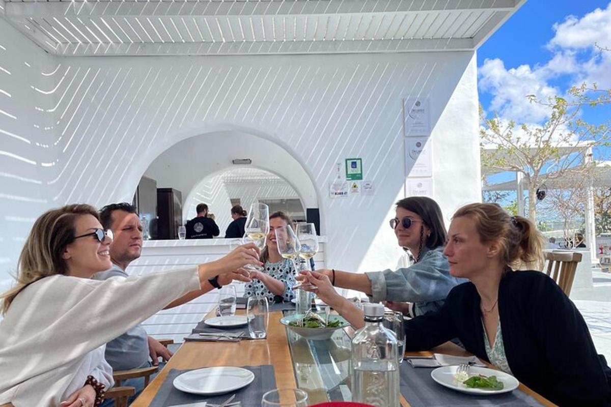 Un grupo de personas sentadas alrededor de una mesa bebiendo vino.