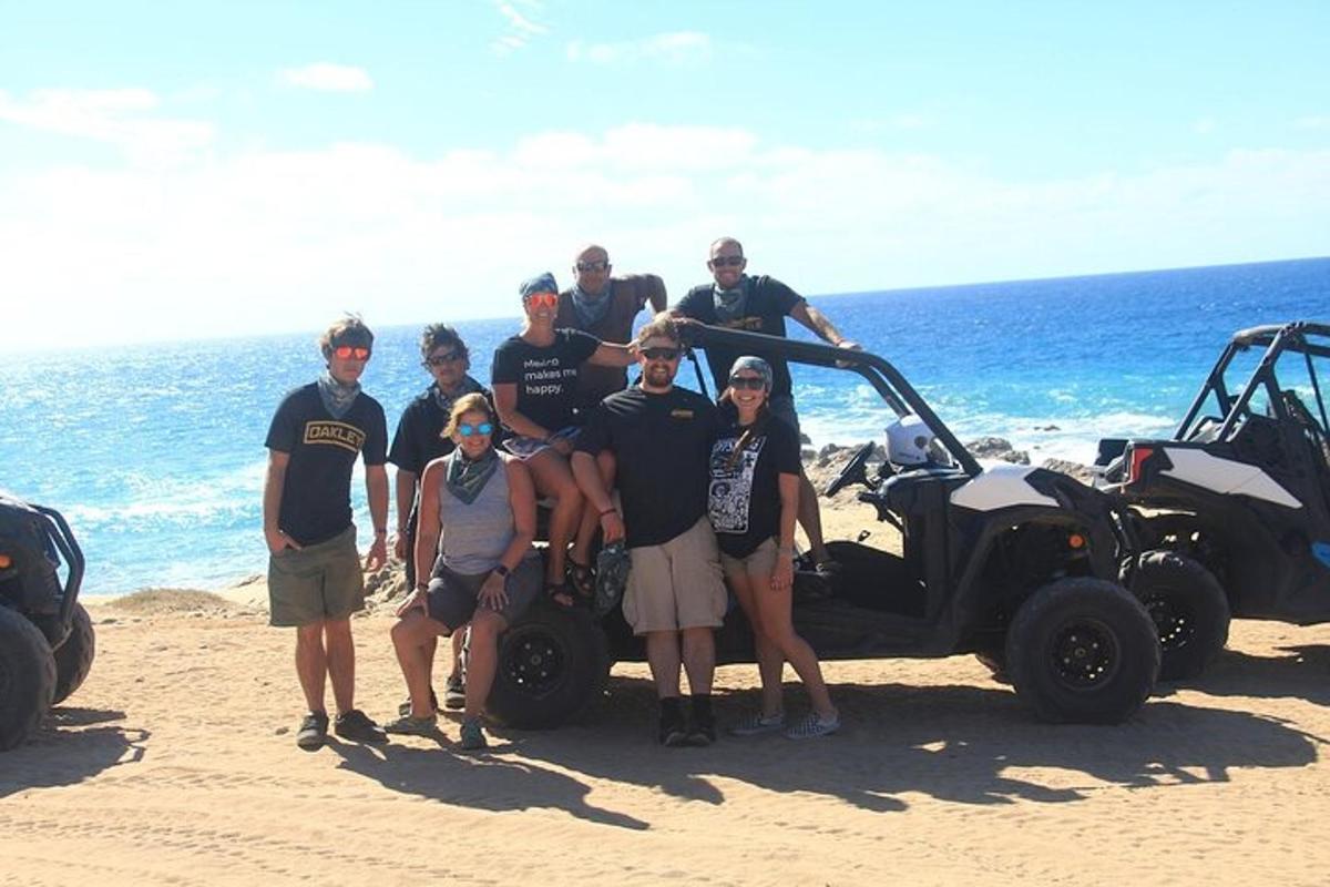 Un grupo de personas de pie junto a un carrito de golf en la playa.