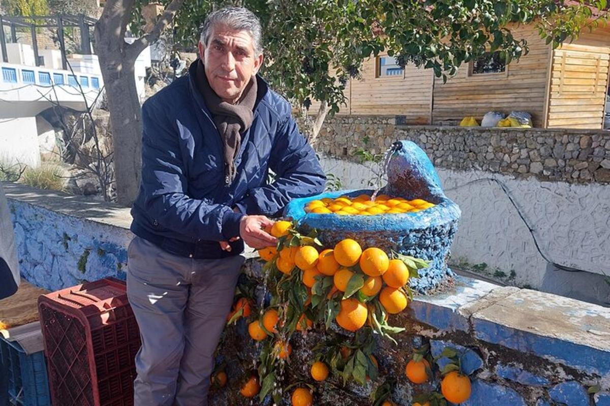 un bărbat care stă lângă o grămadă de portocale
