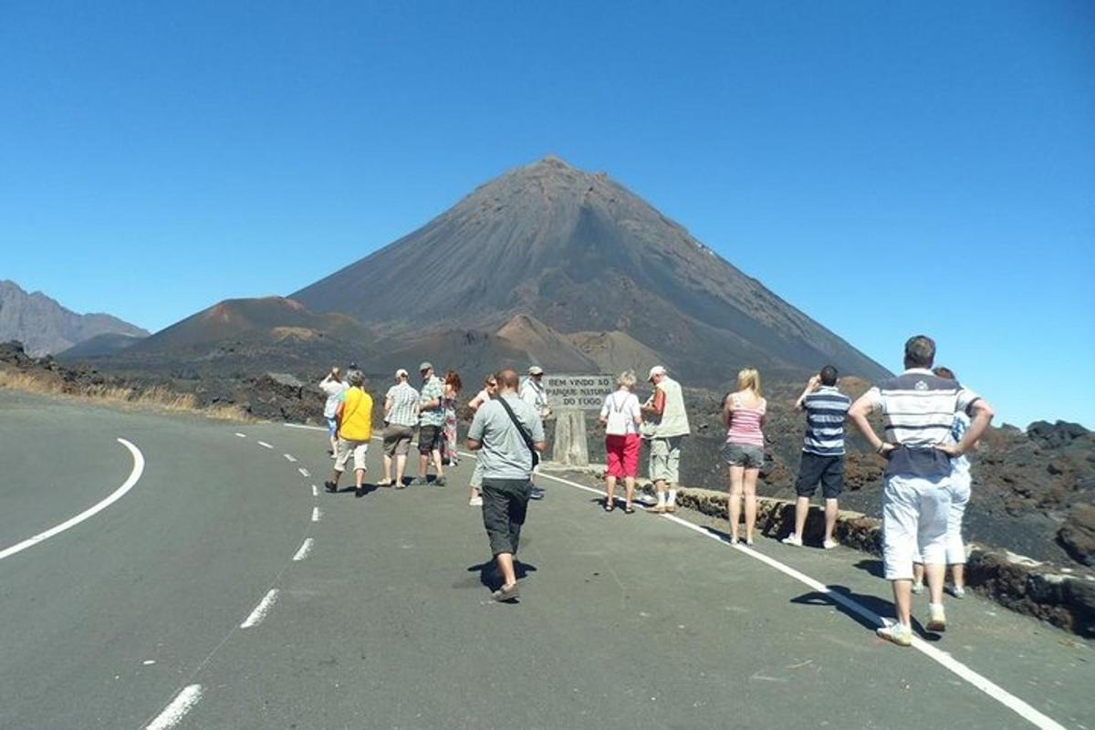 a group of people walking down a road with a mountain in the background