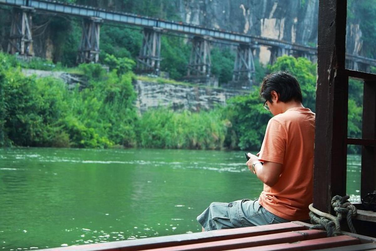 một người đàn ông ngồi trên băng ghế nhìn vào điện thoại di động của mình