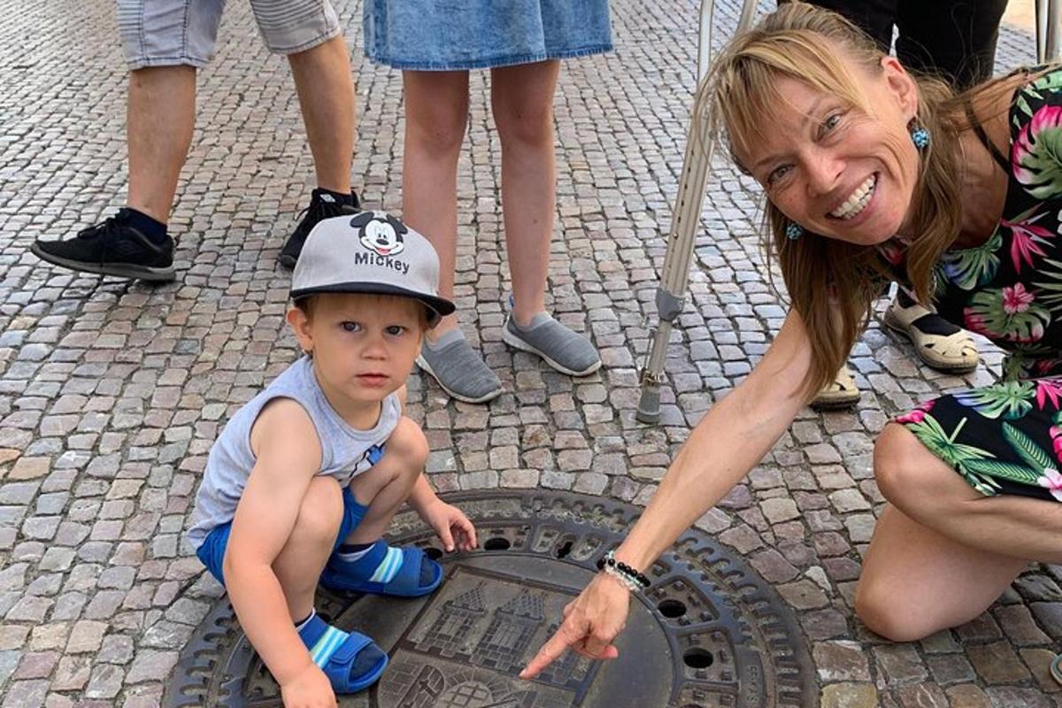 naine osutab kaevuluugi peal olevale lapsele