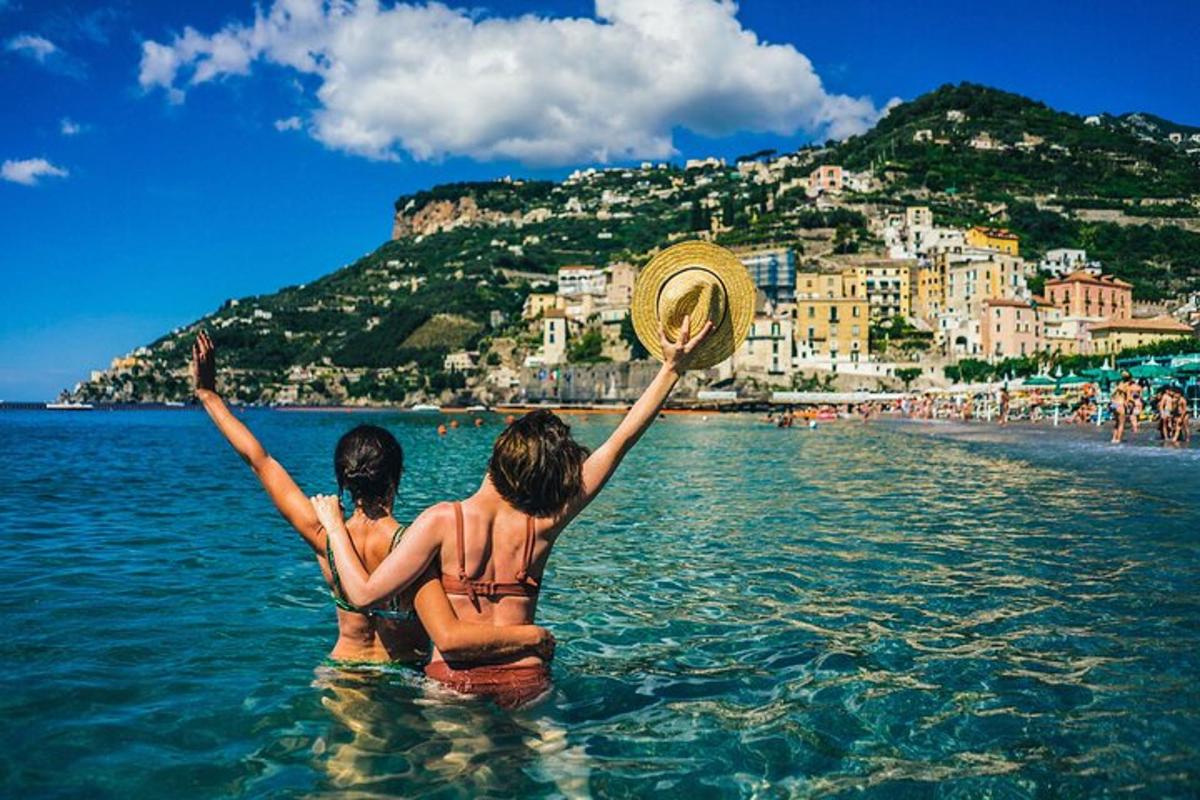 duas mulheres estão sentadas na água em uma praia