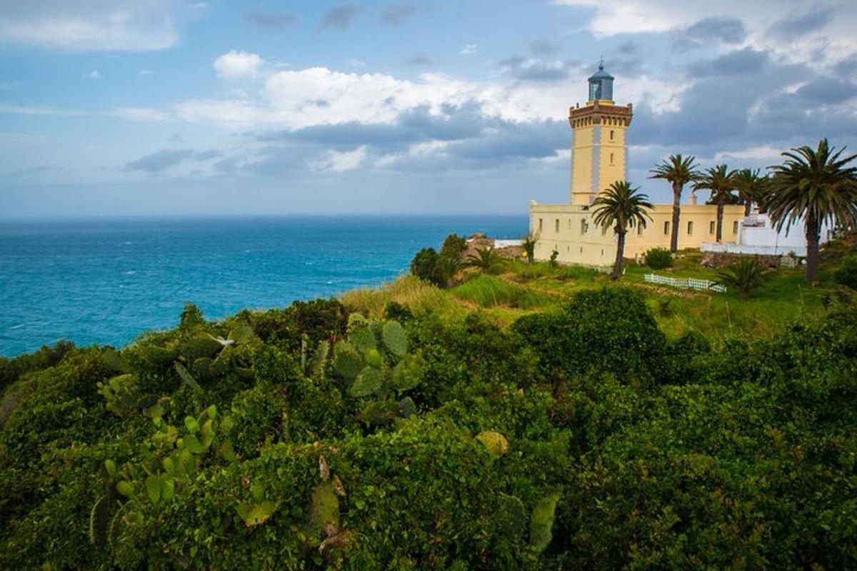 a lighthouse on a hill next to the ocean