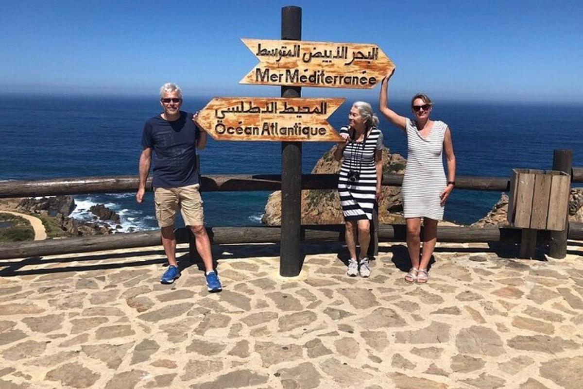 three people standing in front of a sign at the ocean