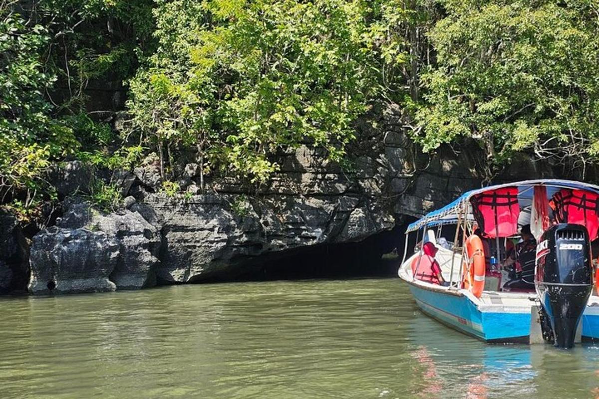 perahu biru di air di sebelah tebing