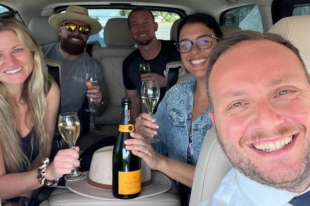 eine Gruppe von Menschen sitzt in einem Auto und hält Weingläser