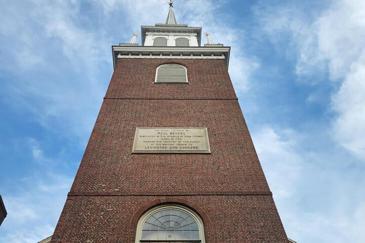 een hoge bakstenen klokkentoren met een plaquette erop