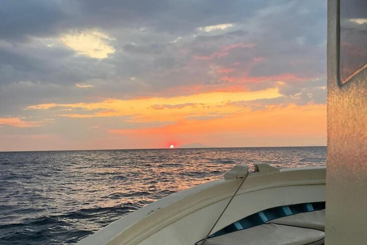 čoln v oceanu s sončnim zahodom