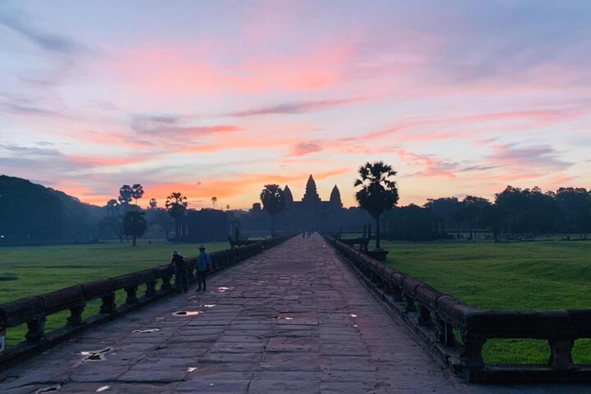 duas pessoas caminhando por uma passarela de pedra ao pôr do sol