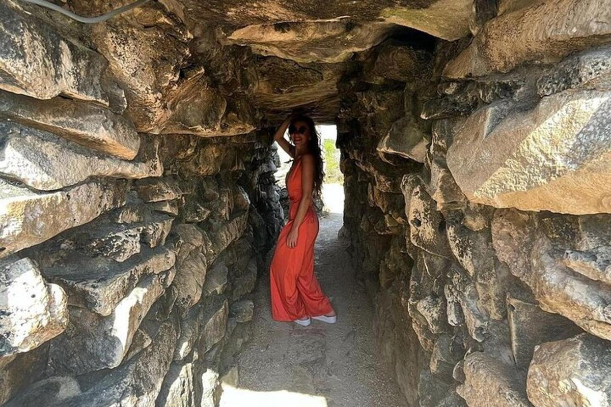a woman in a red dress standing in a stone wall