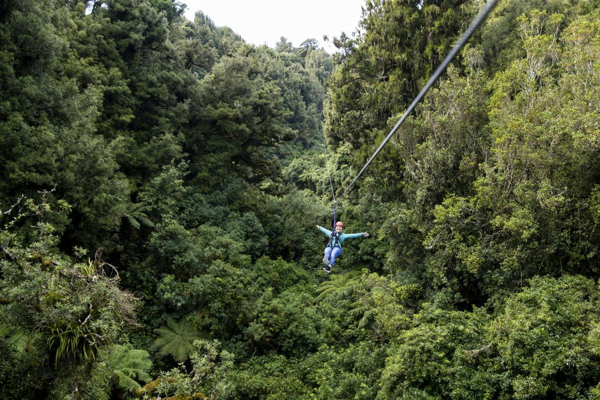 a man on a zip line through the forest