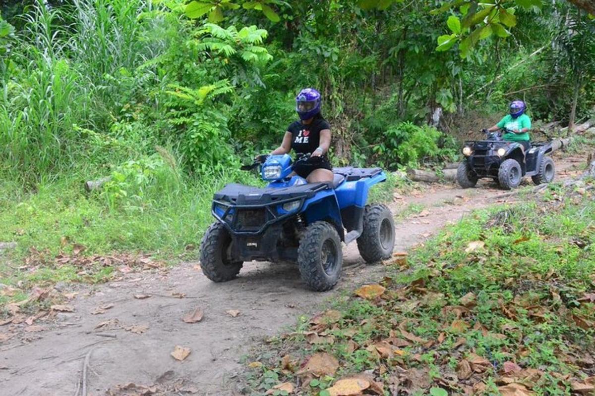 două persoane care călătoresc pe ATV-uri pe un drum de pământ