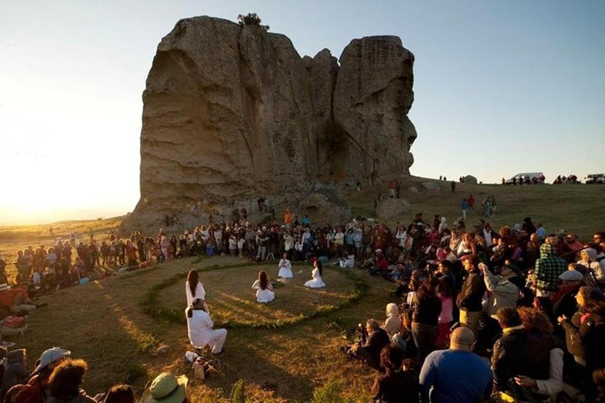 a large crowd of people standing around a large rock