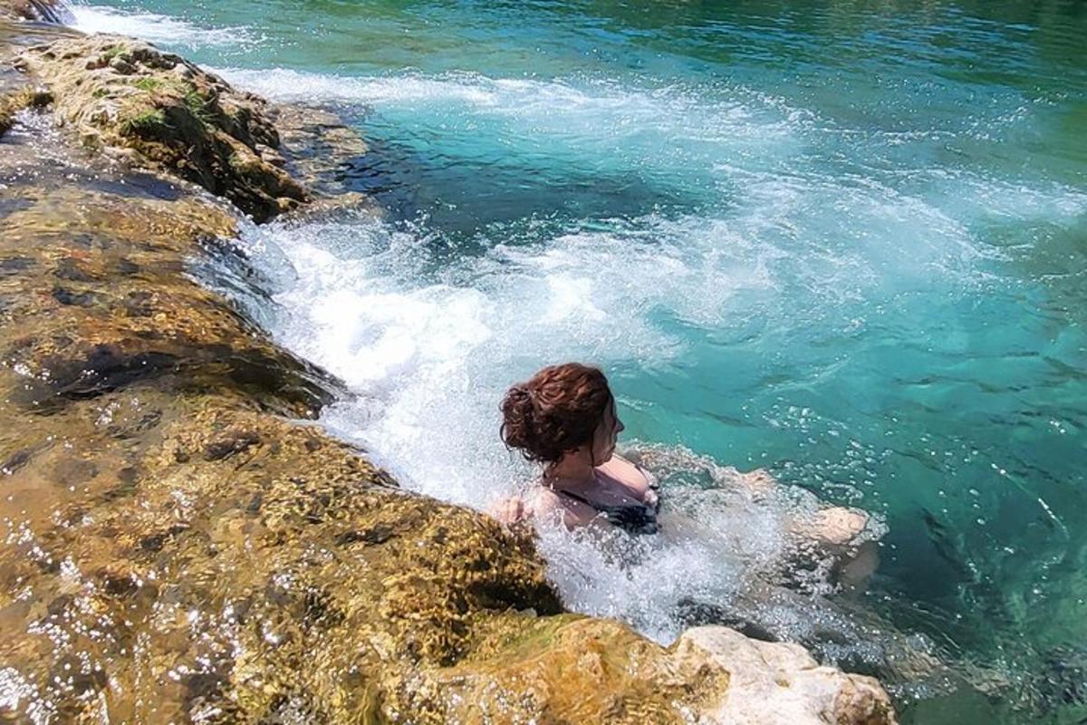 a woman is in the water next to some rocks