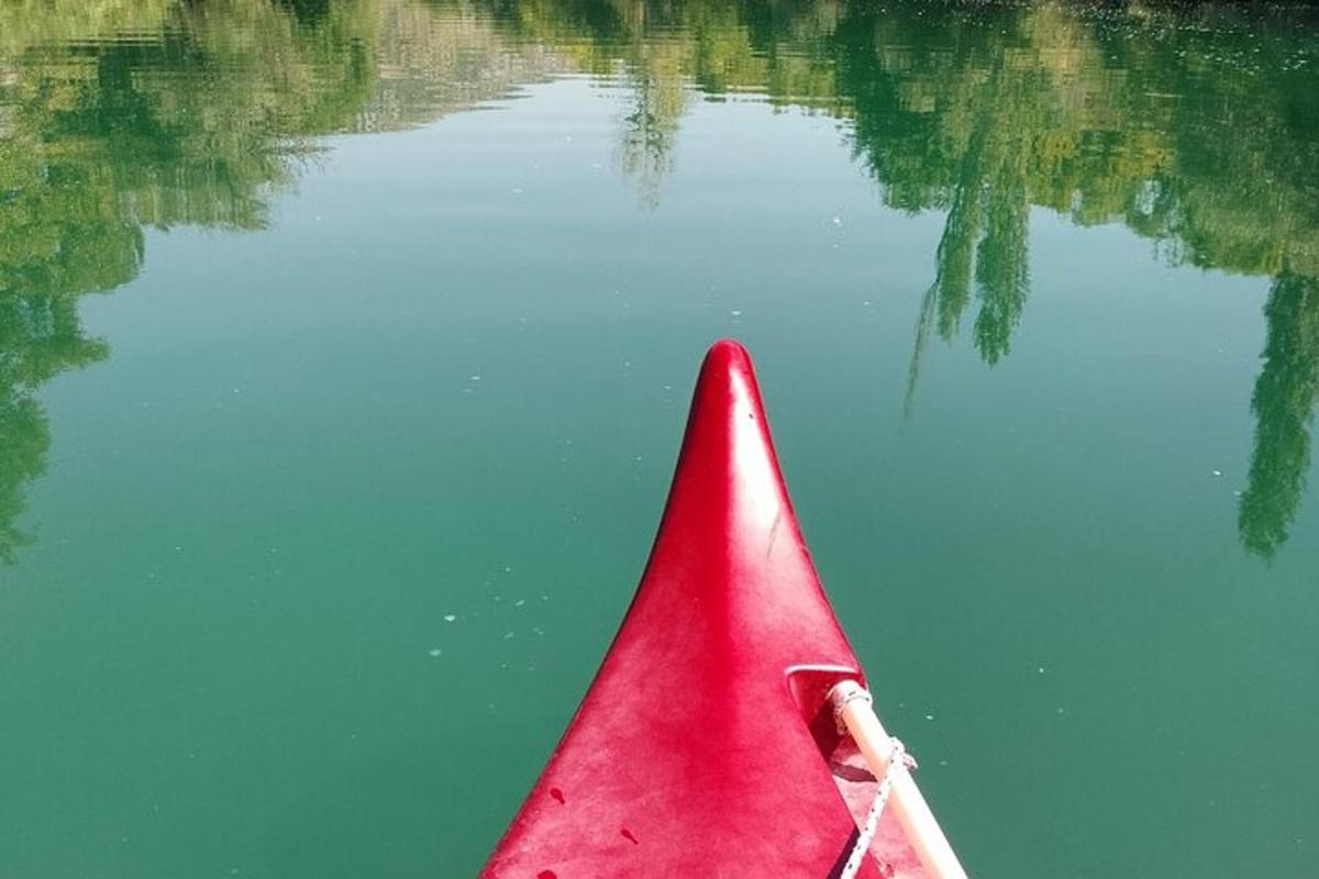 a red kayak in the water with a reflection in the water