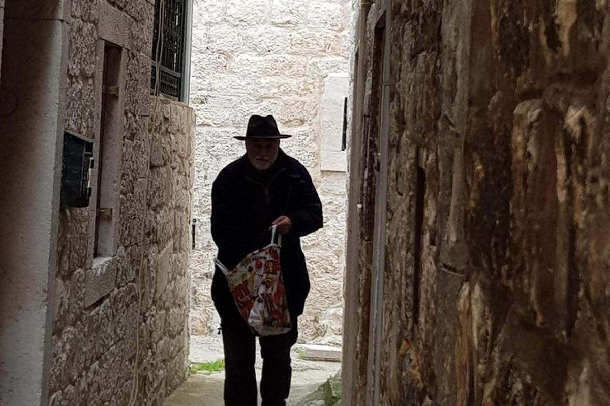muž v klobouku kráčející uličkou