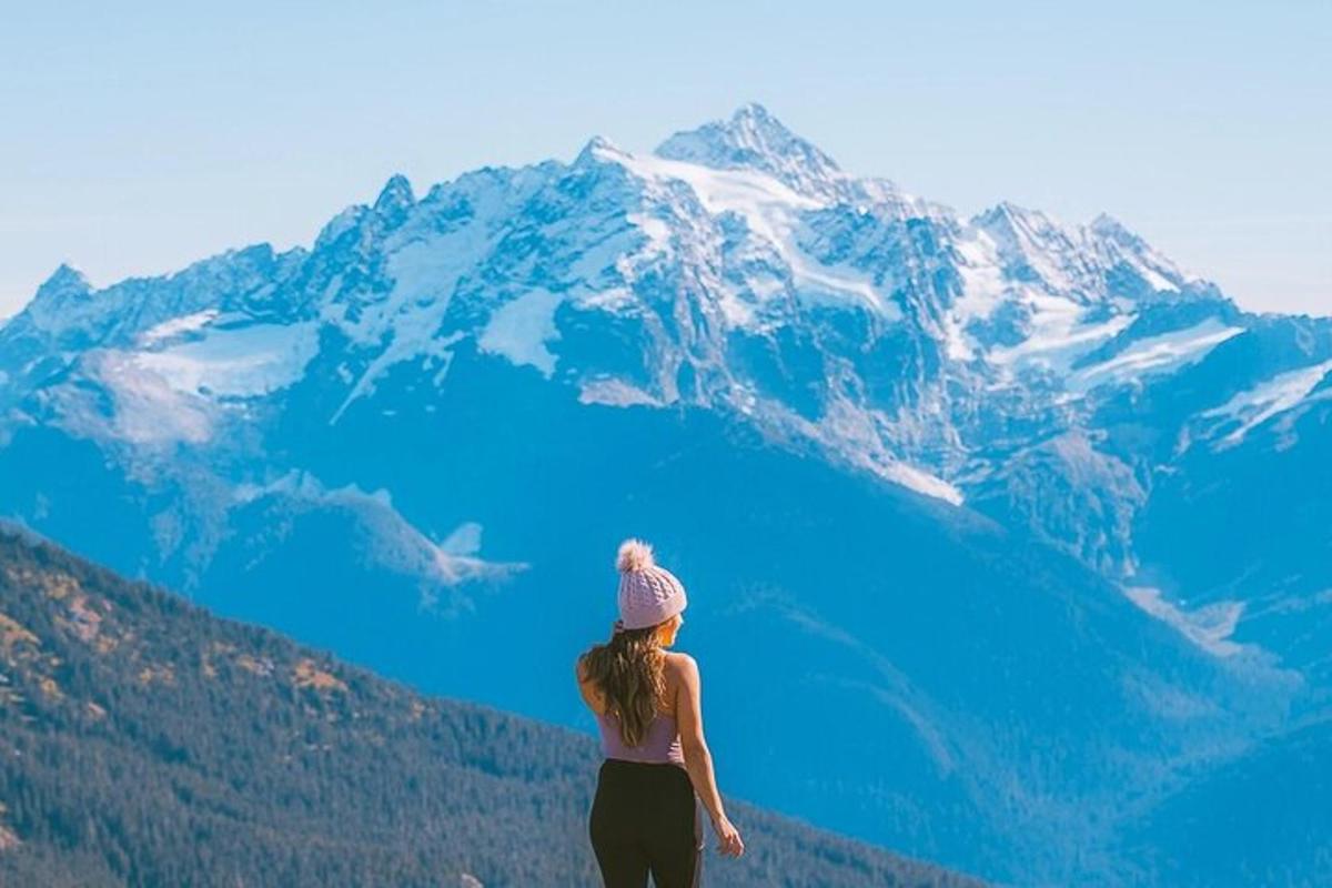 una donna in piedi sulla cima di una montagna con acqua blu