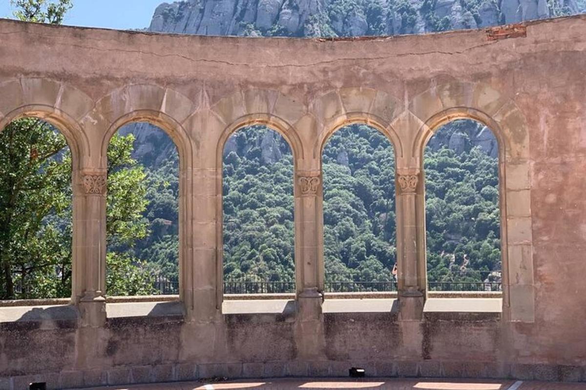 Un edificio de piedra con cuatro ventanas arqueadas con árboles al fondo.