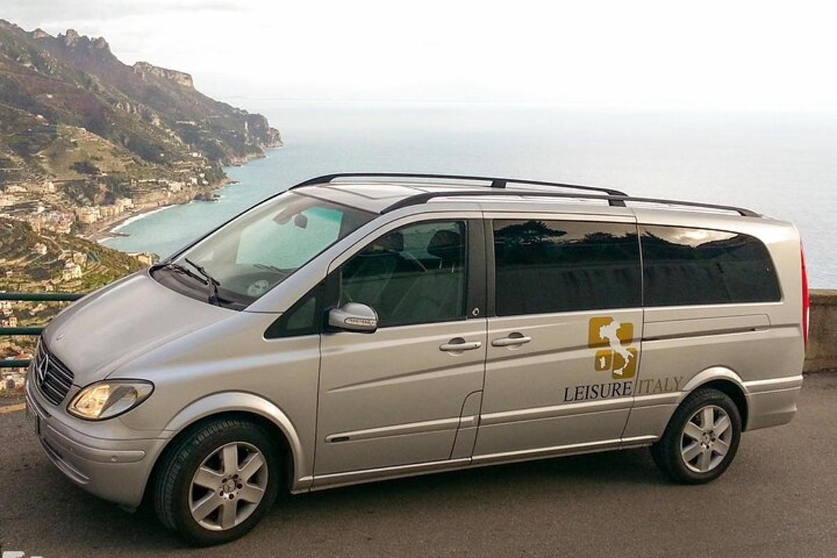 a small silver van parked next to the ocean